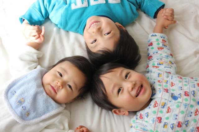 3人の子供が寝転がって笑っている写真
