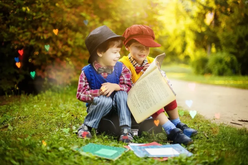 芝生に座って本を読む2人の男の子