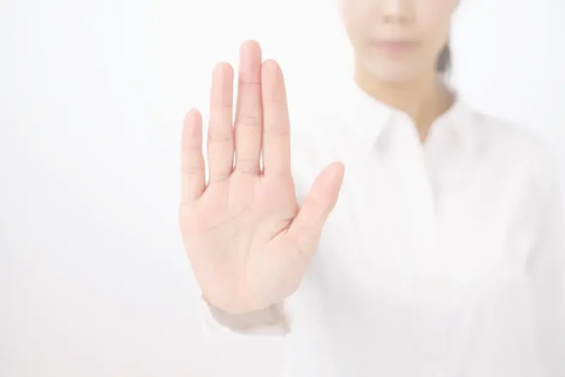 手を前に出して断りの態度を示している女性