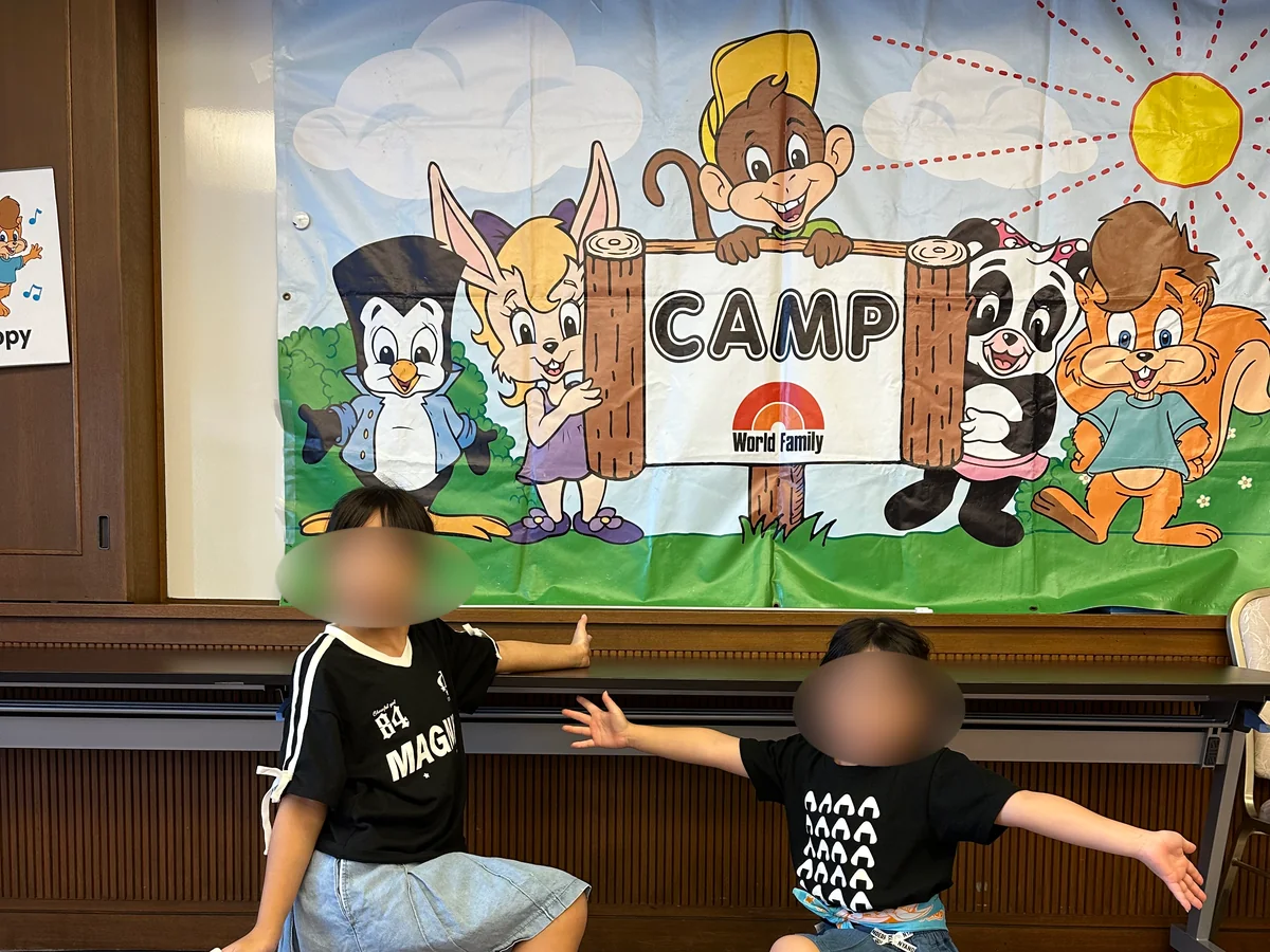 ワールド・ファミリー・キャンプの垂れ幕の前で記念撮影する子どもたち